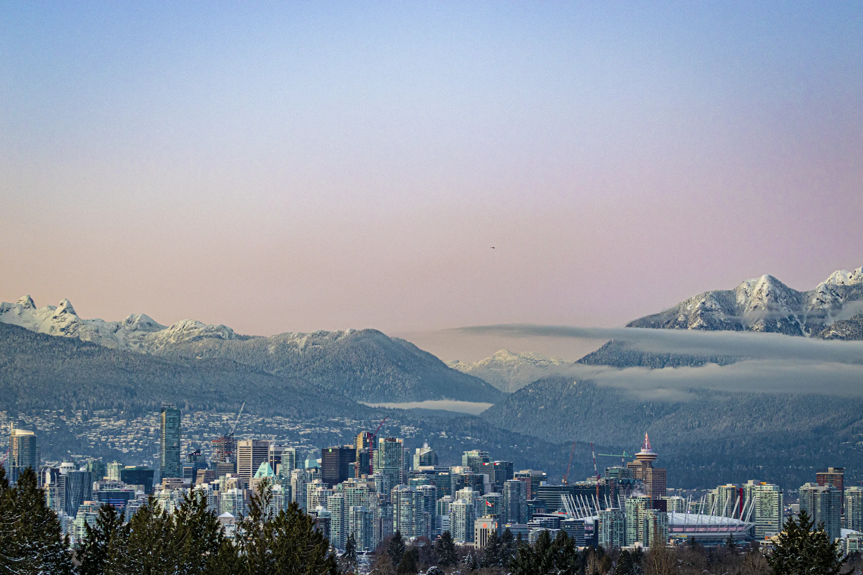 Vancouver's towers beneath snow-covered North Shore mountains in pastel winter light