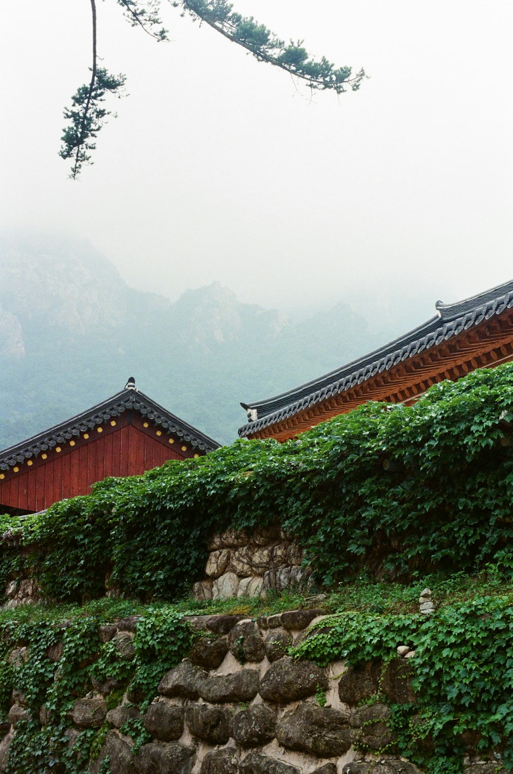 a stone wall with a building and a mountain in the background