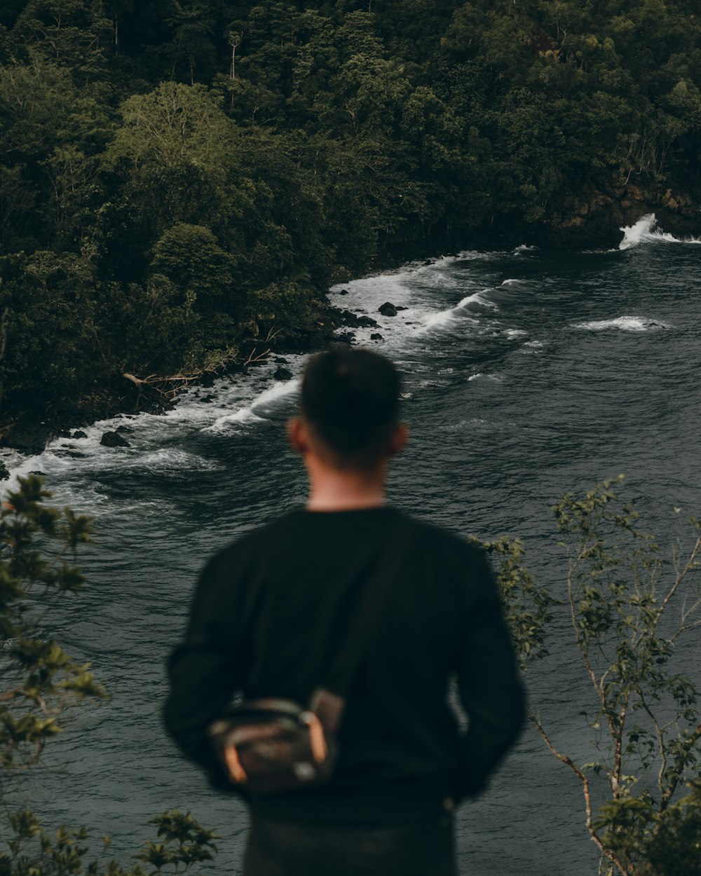 a man standing in front of a river with a waterfall
