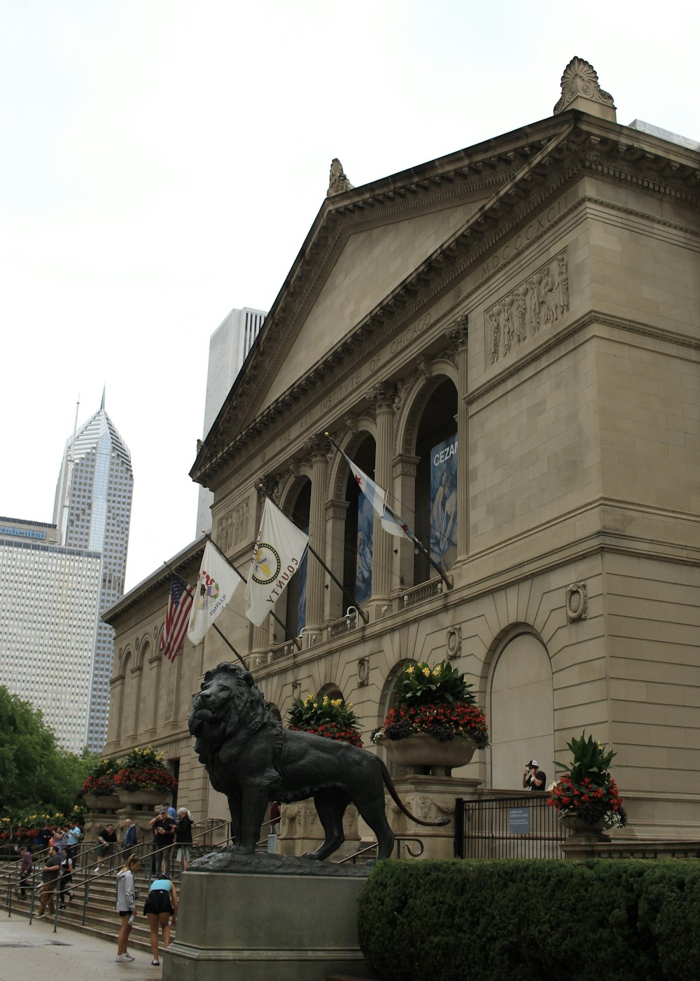 a statue of a lion in front of Art Institute of Chicago with a large clock tower