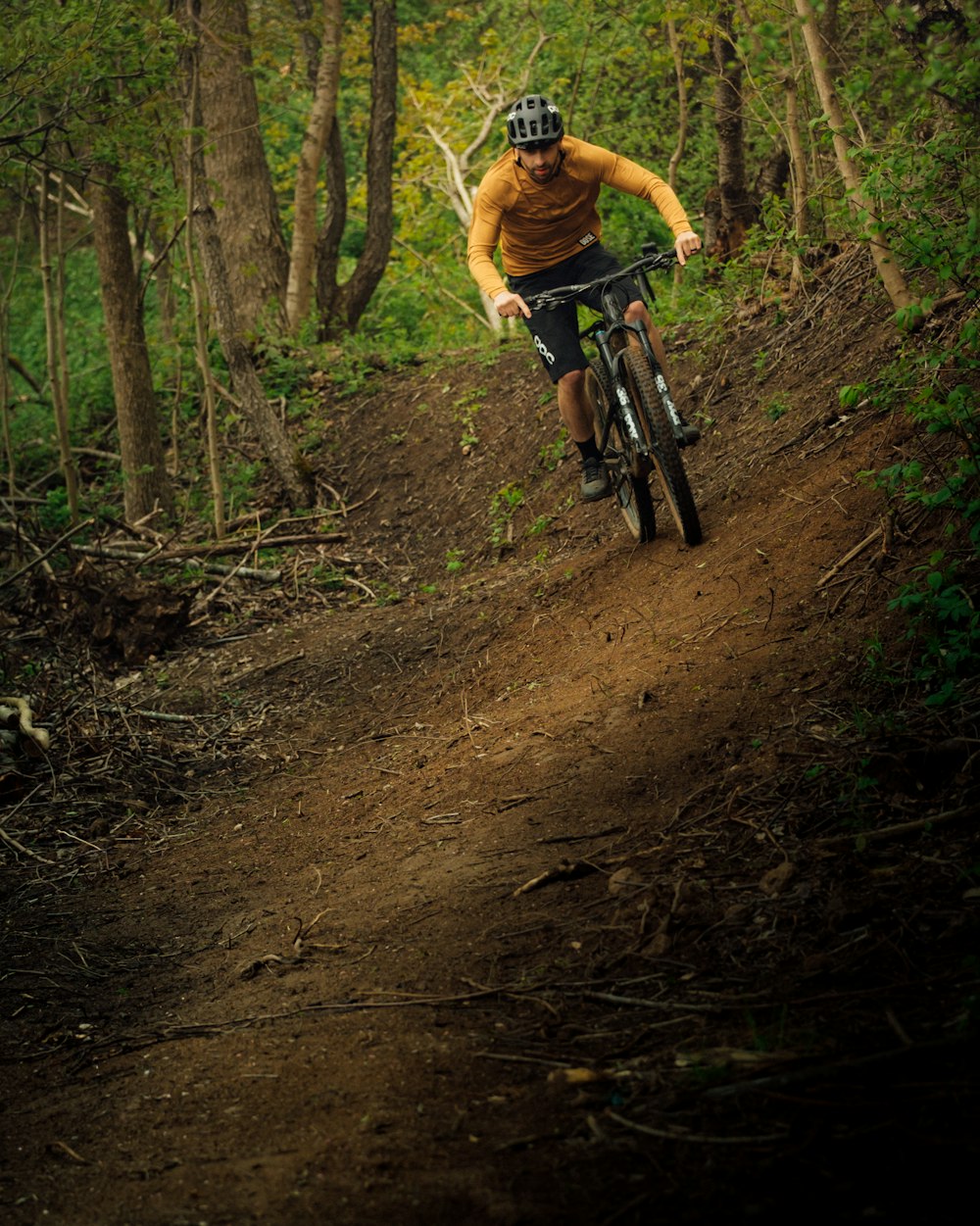 a man riding a bike on a dirt trail in the woods