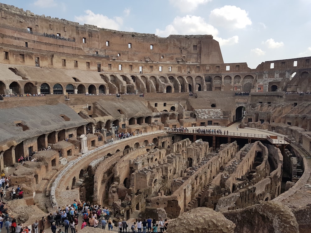 a large ancient building with many people in front of it with Colosseum in the background