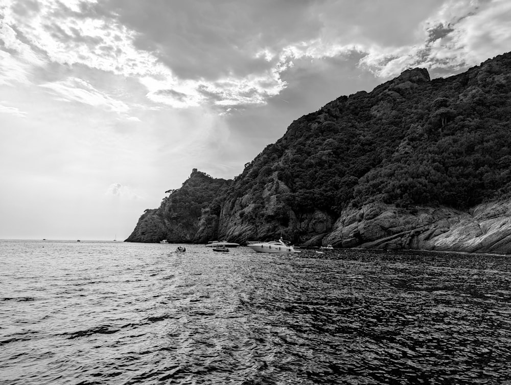 a body of water with a rocky cliff and boats in it