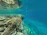 A happy tourist snorkeling among colorful coral reefs in clear blue water.