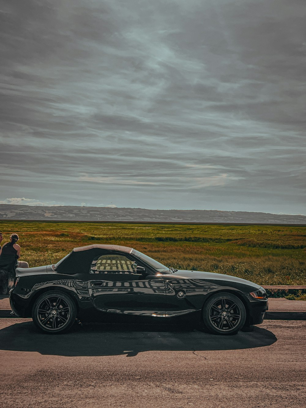 a black sports car parked on a road with a field in the background