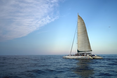 A luxurious sailboat gliding through calm ocean waters under a clear blue sky.
