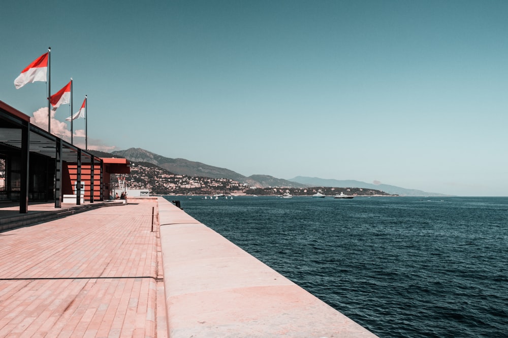 a walkway over water with flags on the side