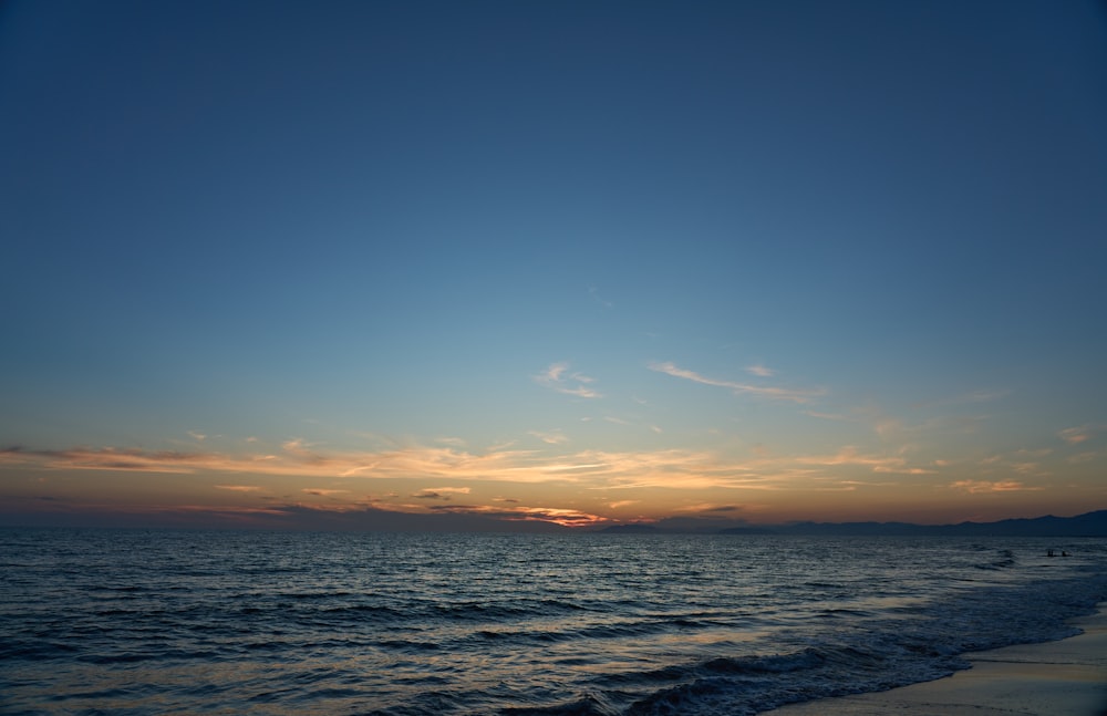 a beach with a body of water and a sunset