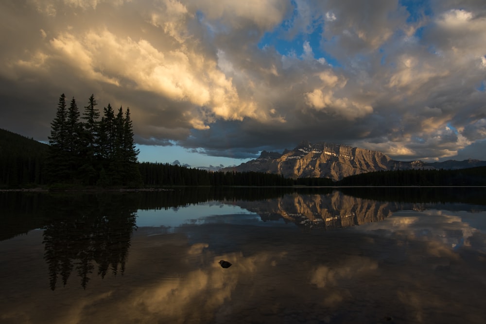 a lake with trees and mountains in the background