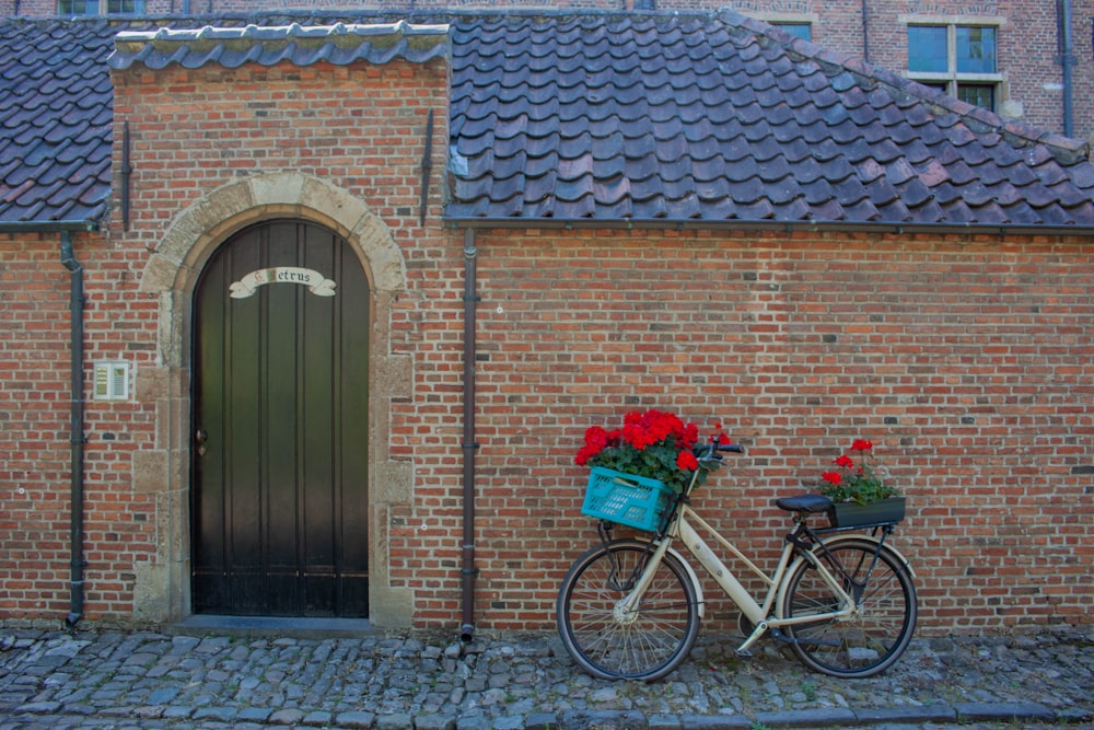 a bicycle parked in front of a brick building with flowers in the basket