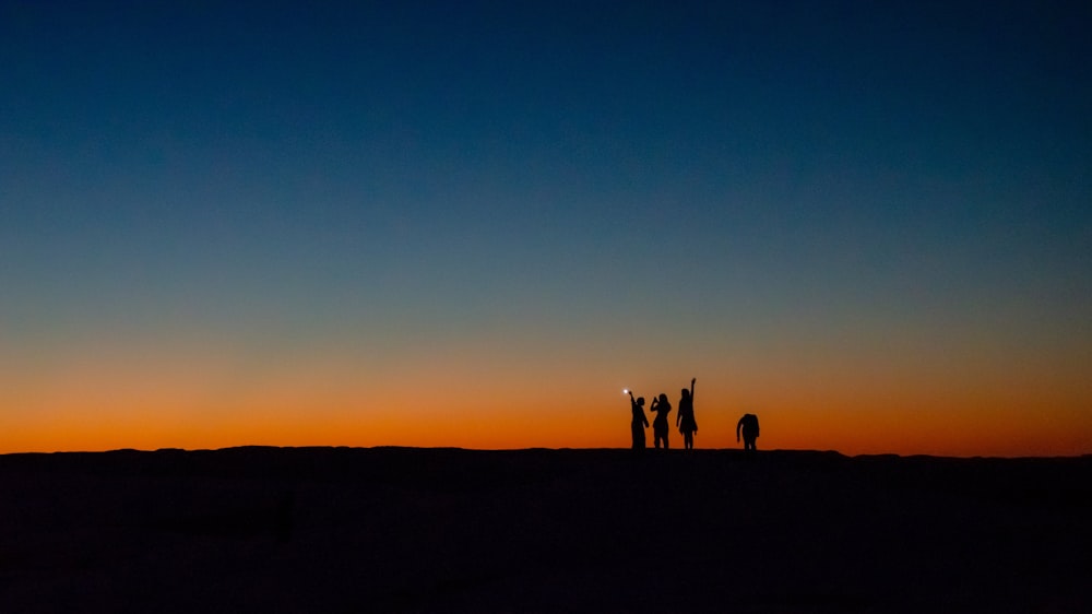 a group of people standing in front of a sunset
