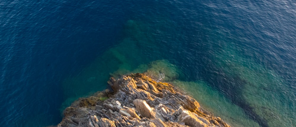 a rocky cliff with a body of water in the background