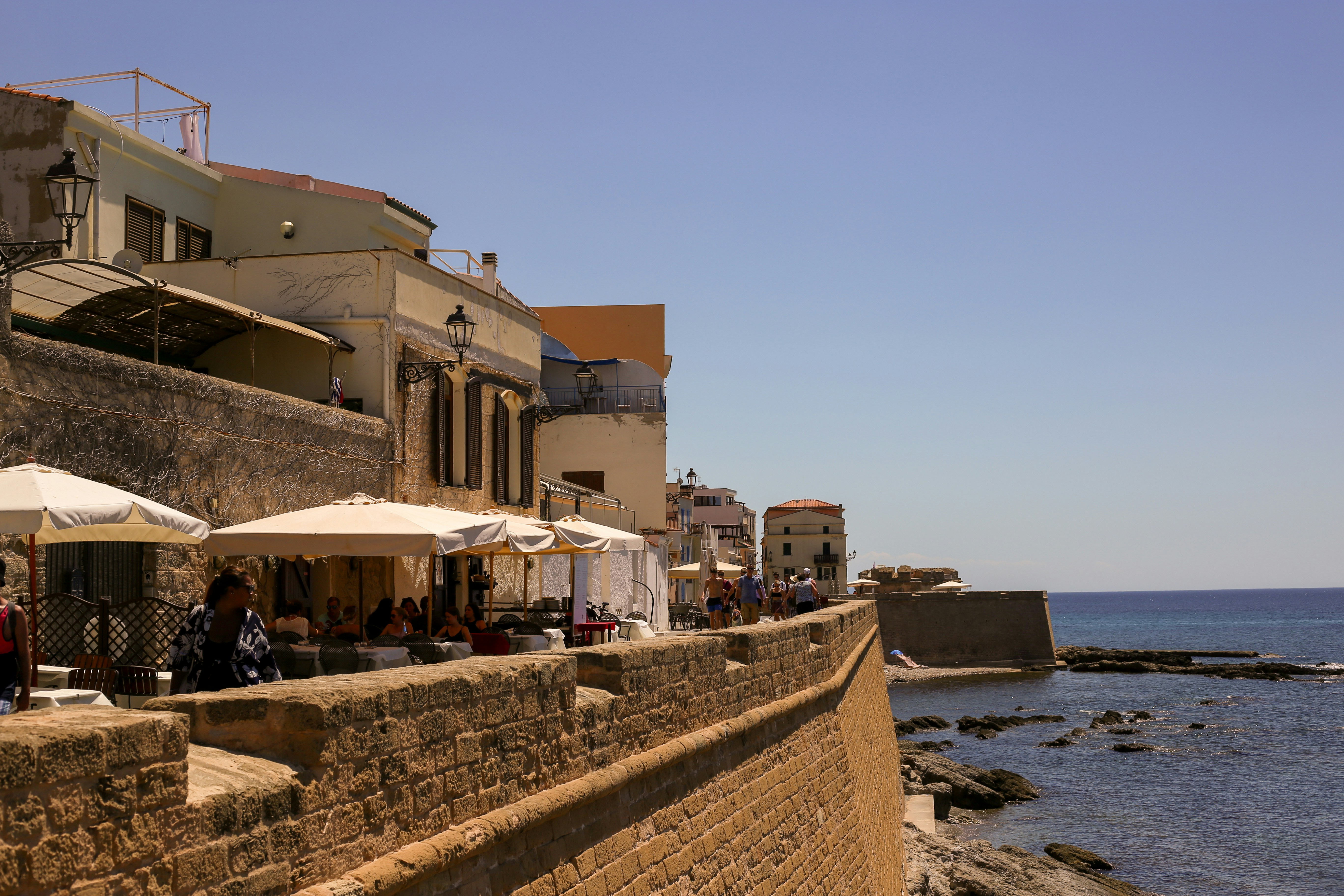 a stone wall with umbrellas and a stone wall by the water