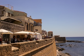 a stone wall with umbrellas and a stone wall by the water