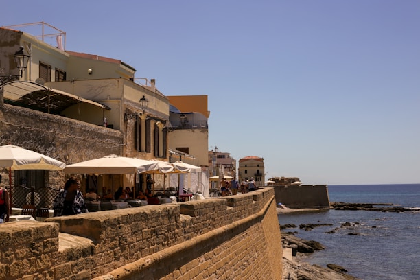 a stone wall with umbrellas and a stone wall by the water
