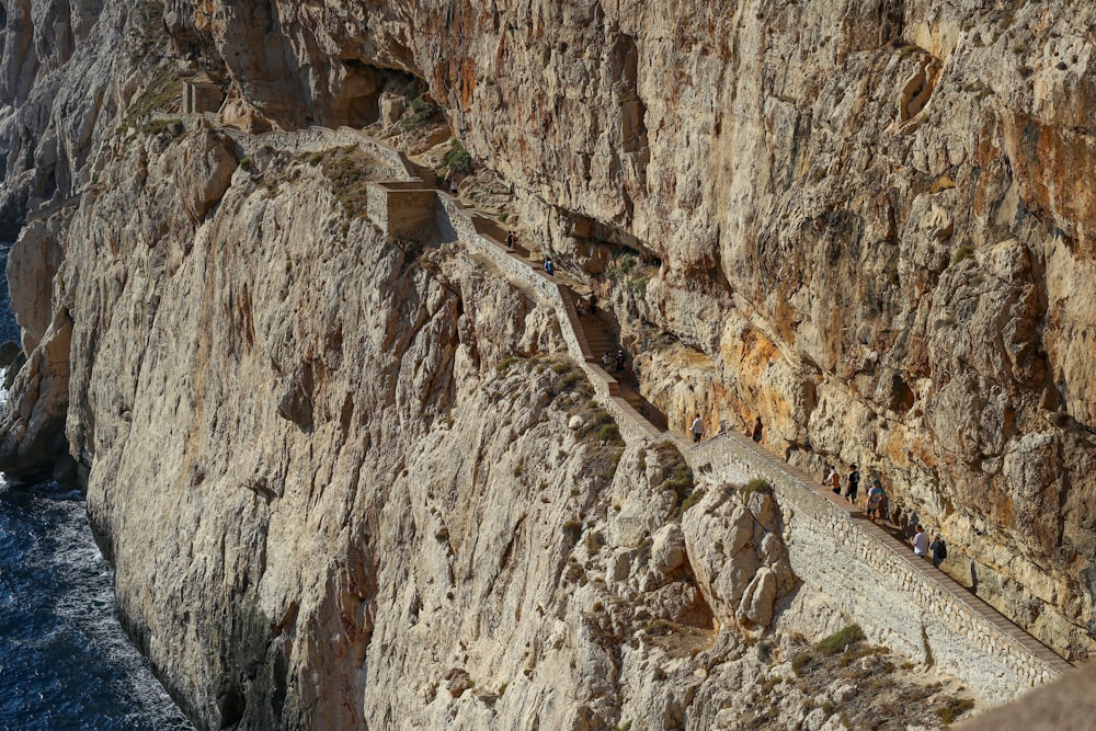 Menschen, die auf einem Weg zwischen großen Felsen gehen