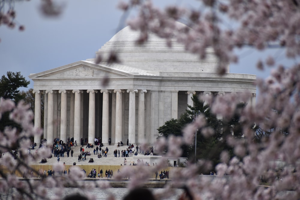 a large white building with columns and people standing in front of it