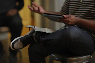 Hands navigating through a cloud networking certification guide on a tablet against a soft blue background.
