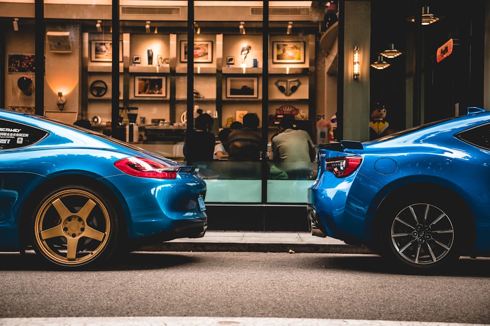 a couple of blue cars parked in a showroom