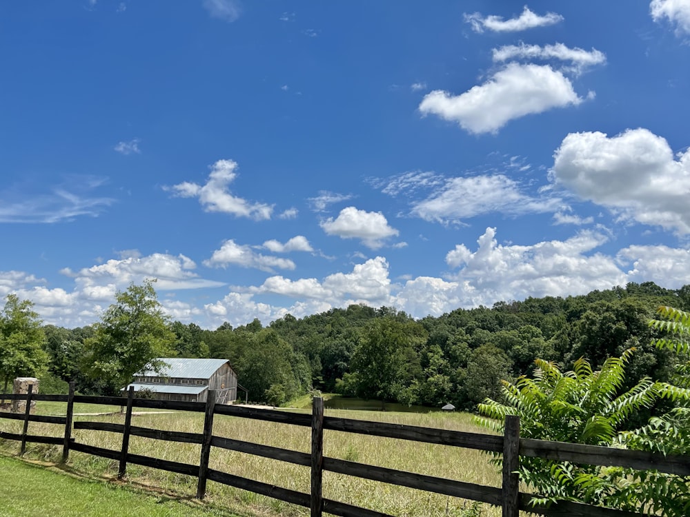 a fence in front of a field of trees and a house