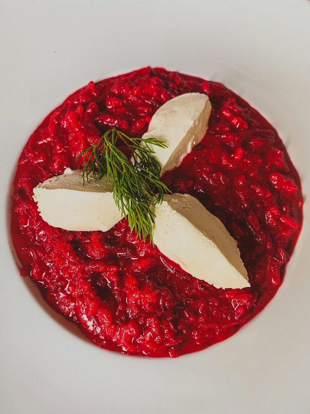 un trozo de comida roja con una hoja verde en la parte superior