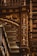 An intricately designed wooden column adorned with ornate carvings in gold, featuring floral patterns and elegant details. The background includes shelves filled with books, highlighting the setting in an opulent library. The column includes an inscription reading 'Rocha Pitta'.