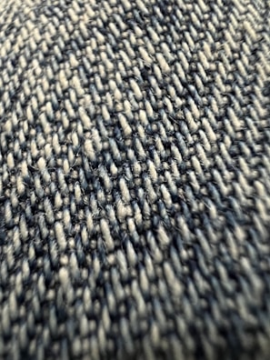 Close-up view of a textured fabric with tightly woven fibers, exhibiting a pattern of interlocking threads in varying shades.