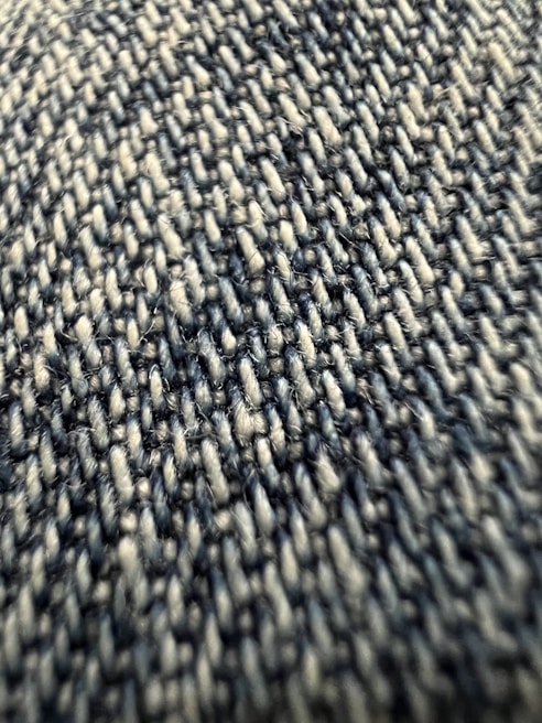 Close-up view of a textured fabric with tightly woven fibers, exhibiting a pattern of interlocking threads in varying shades.