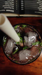 Close-up of a refreshing mojito with mint leaves and lime on a black terrace table at sunset.