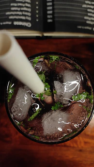 Close-up of a refreshing mojito with mint leaves and lime on a black terrace table at sunset.