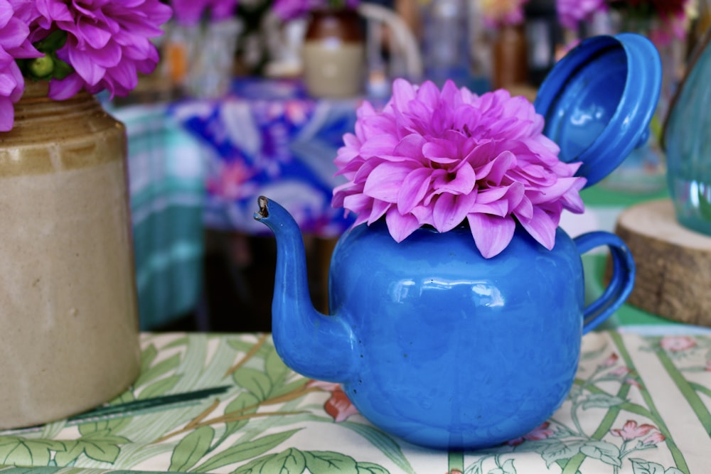 a blue teapot with a pink flower in it
