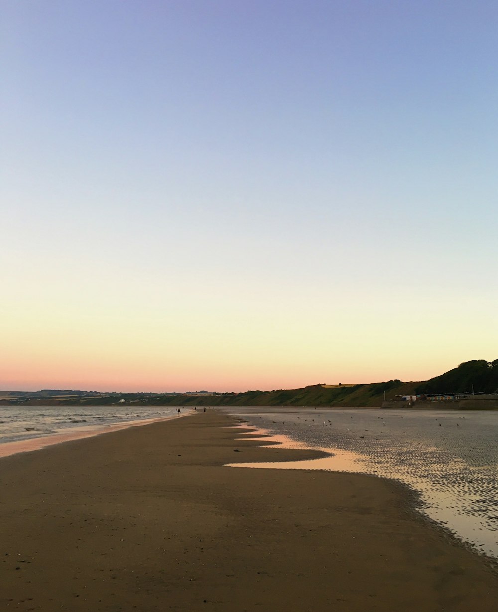 a beach with a body of water and hills in the background