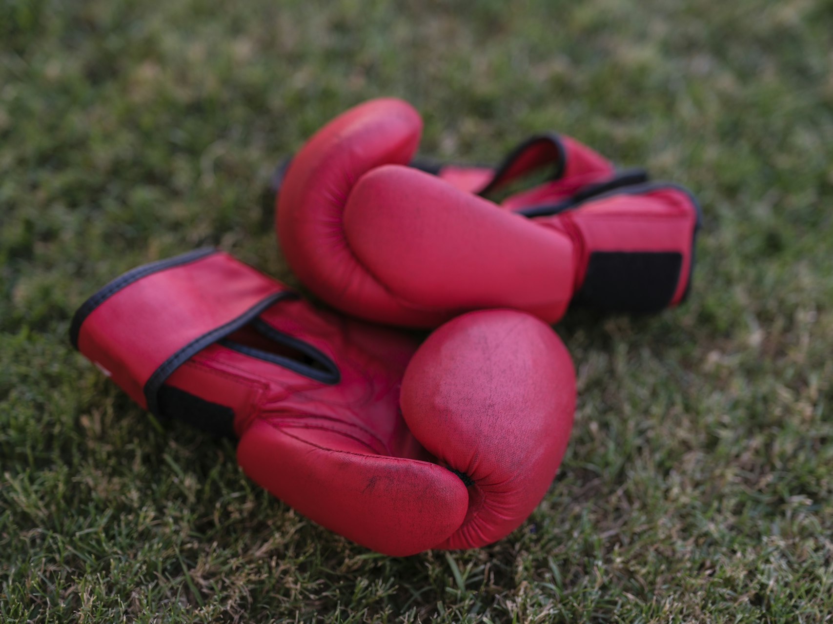 A pair of red boxing gloves resting on the grass