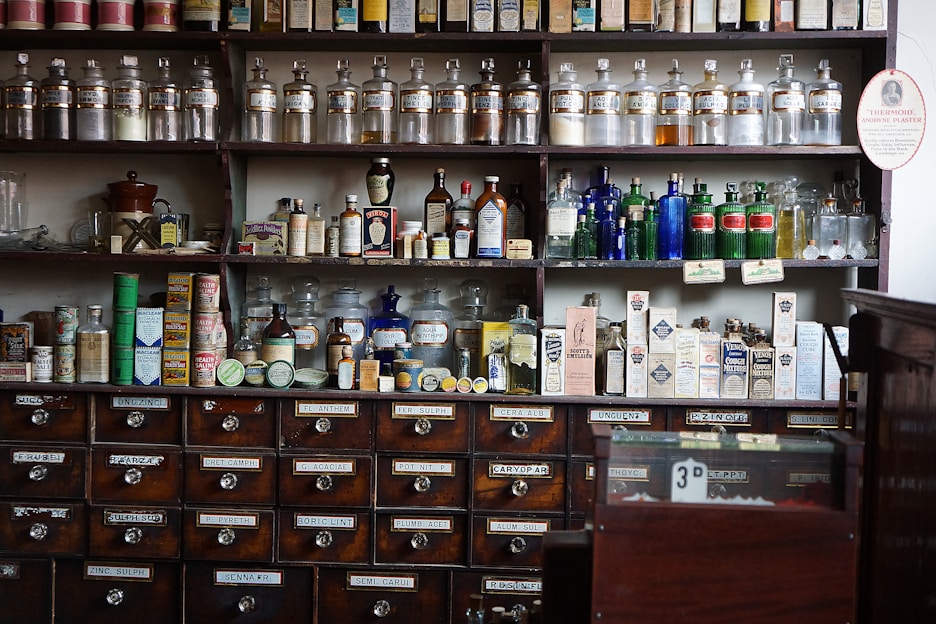 A cozy home pharmacy shelf filled with natural herbal remedies and supplements in glass jars and wooden containers.
