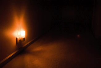 A close-up of a Tiverton emergency light glowing warmly in a dim hallway.