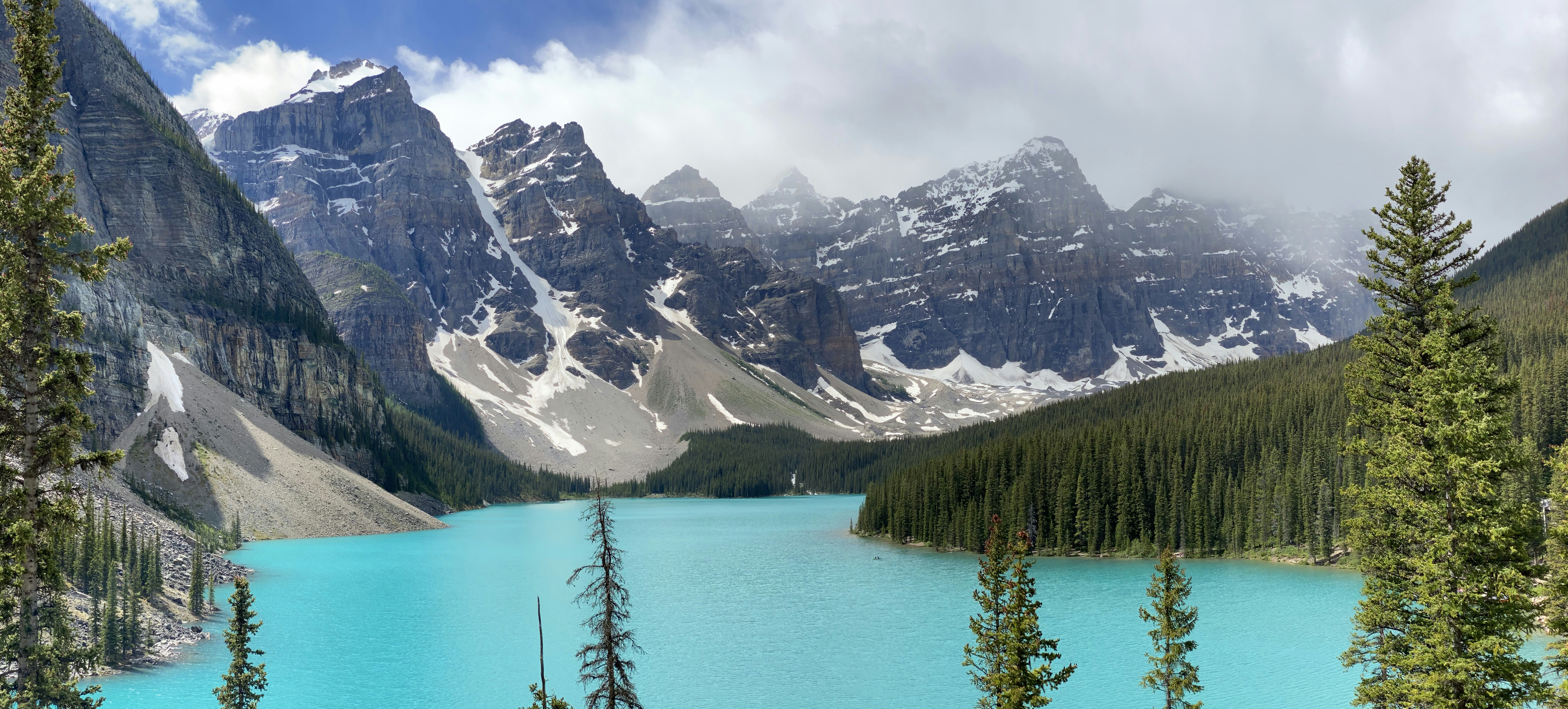 a lake surrounded by mountains, Bright blue glacial waters of Moraine Lake.