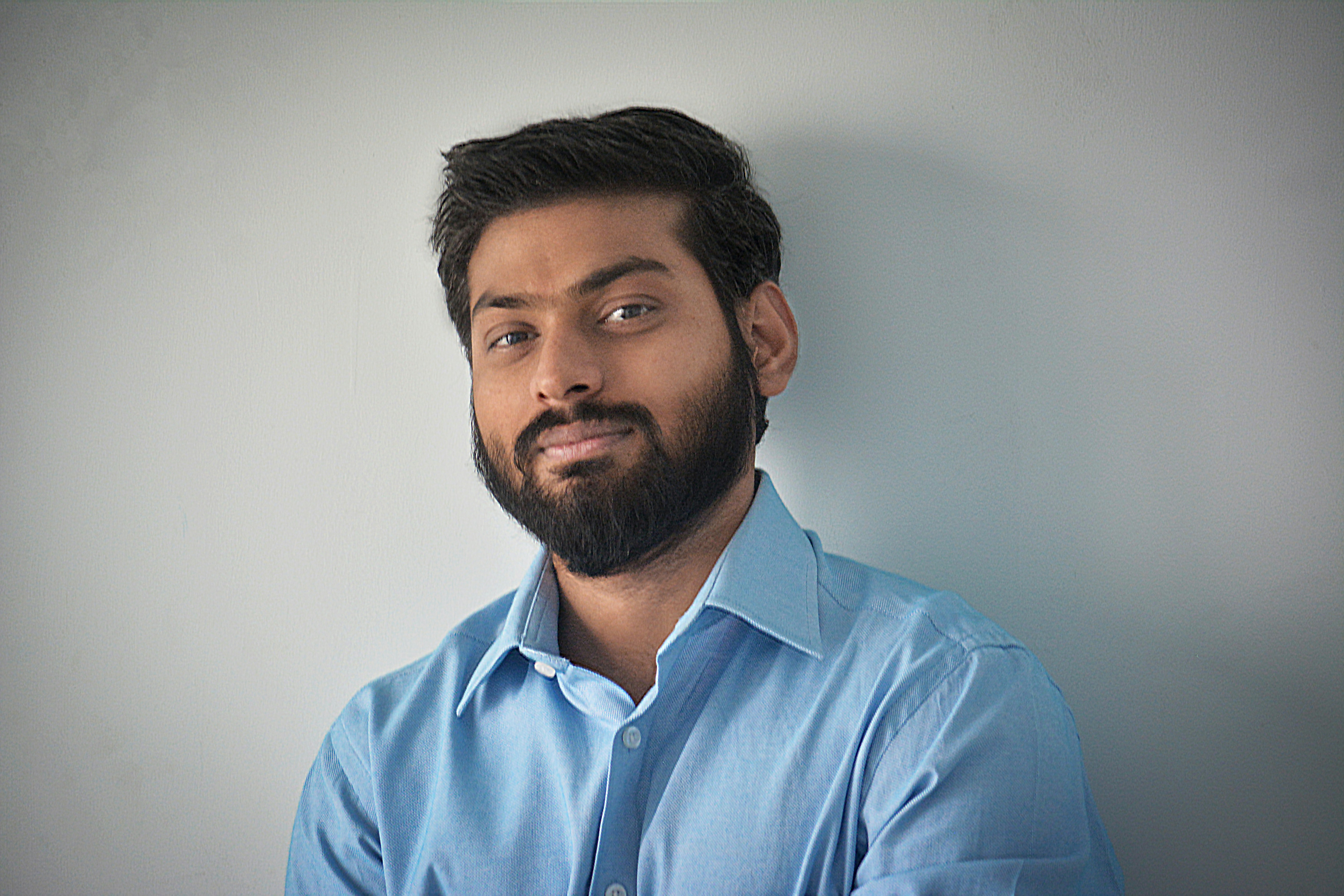 Man with beard smiling confidently, dark background with soft side lighting
