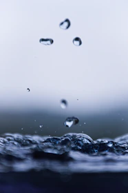 Close-up of crystal clear water droplets falling into a glass.