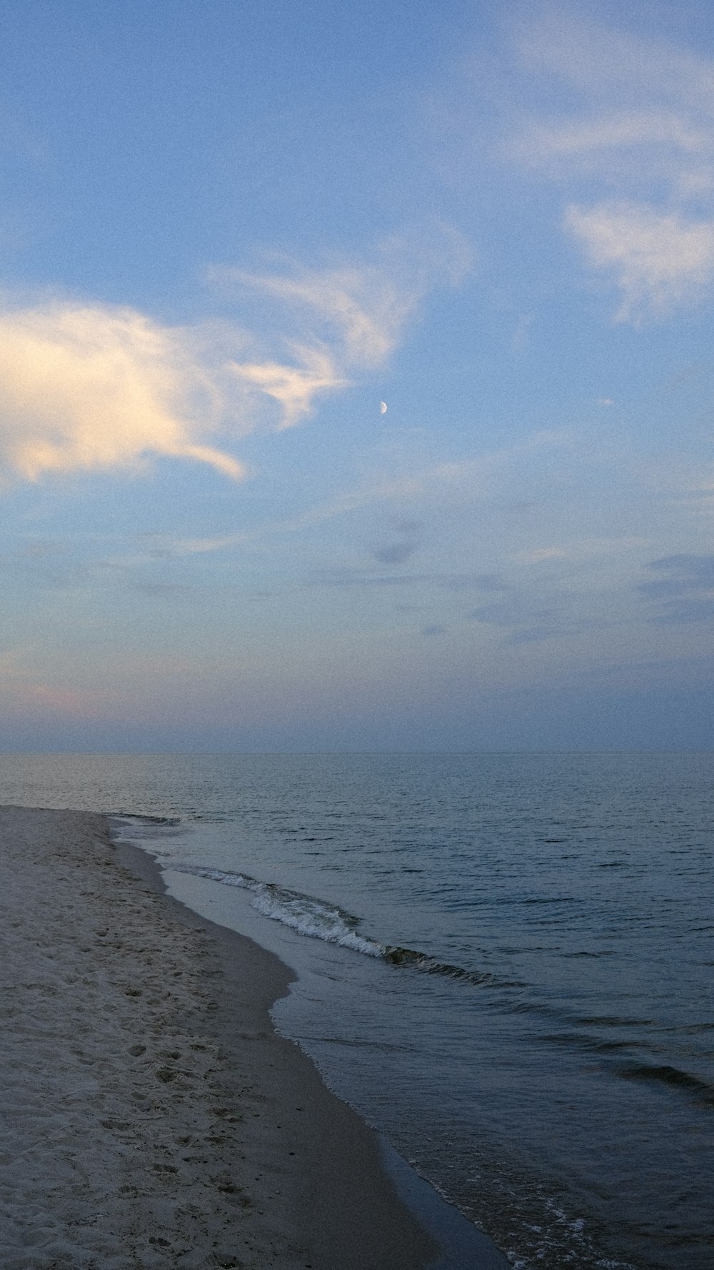 a beach with a body of water and a cloudy sky