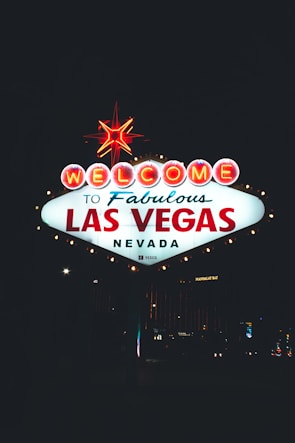 Smiling family holding a 'Sold' sign with the Las Vegas skyline glowing at sunset behind them.