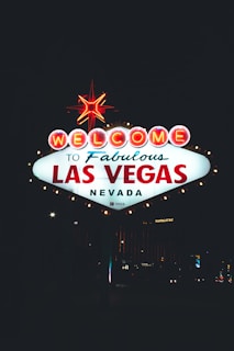 A brightly lit sign against a dark night sky with the words 'Welcome to Fabulous Las Vegas Nevada' in bold lettering. The sign is adorned with a red star on top and surrounded by glowing lights.