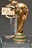 A shiny, golden trophy intricately designed with a globe-like top and detailed engravings sits on a glass shelf. The base is highlighted with green and gold, featuring the words 'FIFA WORLD CUP'. The backdrop includes a glass or acrylic panel etched with 'FIFA MUSEUM'.