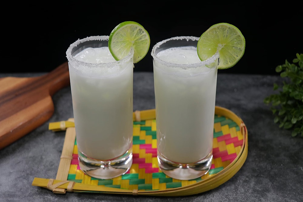 two glasses of drinks with limes