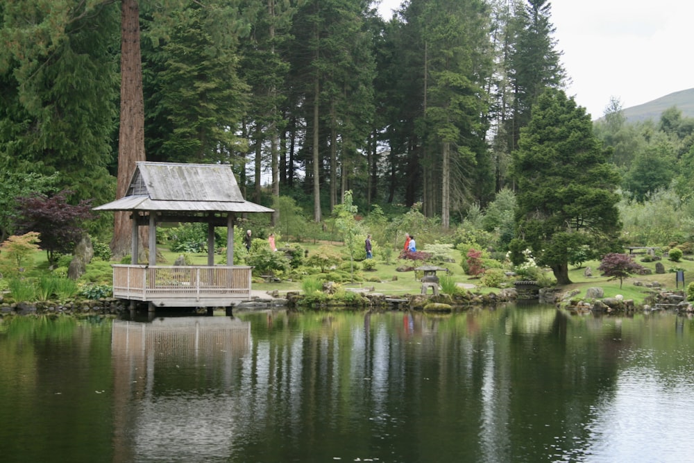 a pond with a small building and trees around it