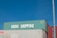 Three stacked shipping containers are visible, with the top one labeled 'China Shipping' in bold white letters. A clear blue sky serves as the background, and there is a vertical metal pole on the right side of the image.