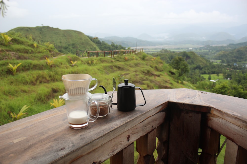 a table with cups and tea cups on it with a grassy hill in the background