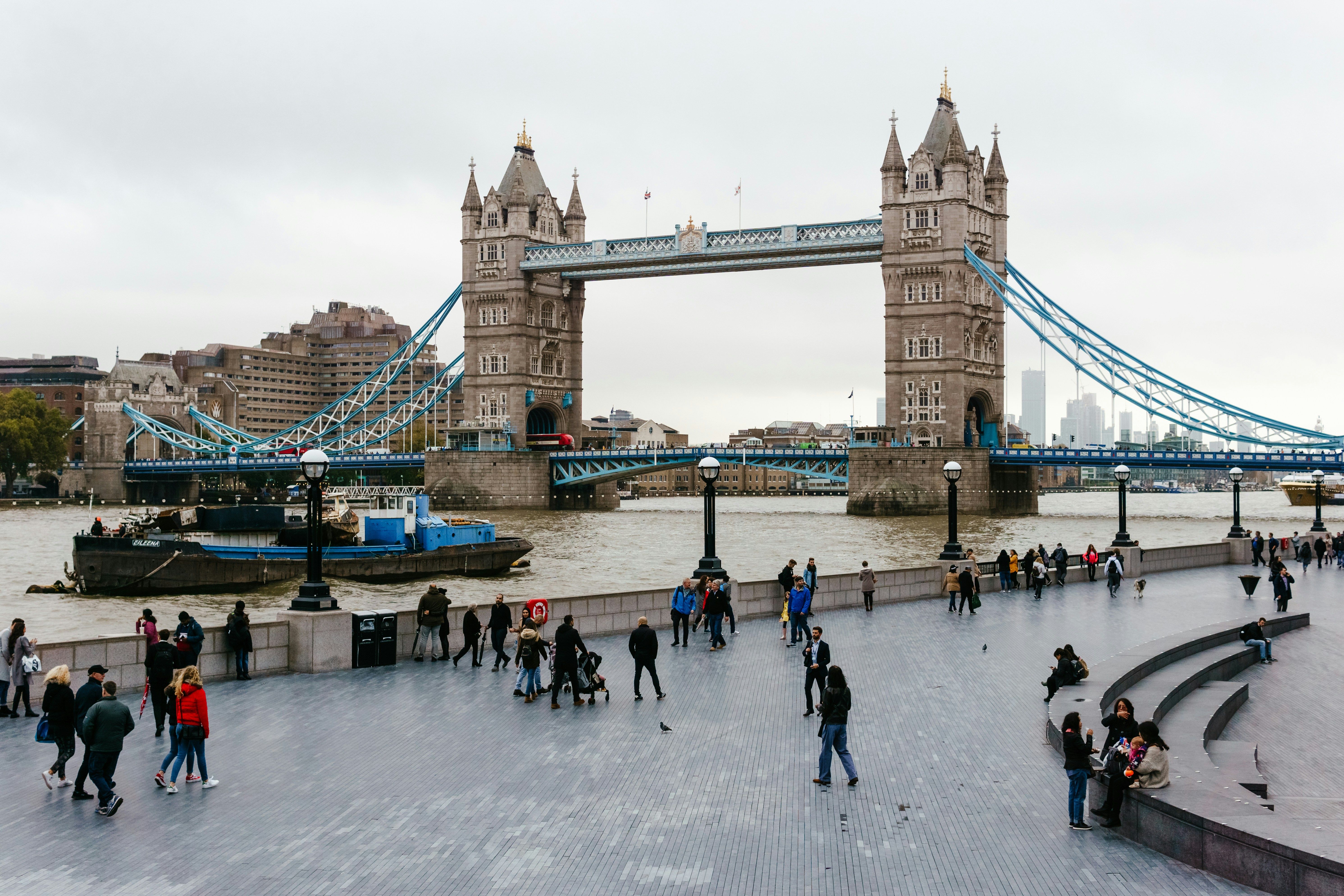 a group of people walking on a frozen river in front of a bridge