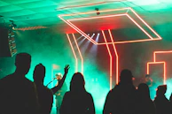 Audience faces illuminated by colorful neon lights during a live set
