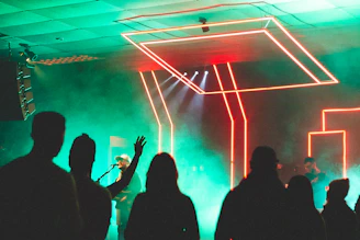 Antonio Fenicelli performing live on stage with vibrant neon blue and purple lights illuminating the club atmosphere.