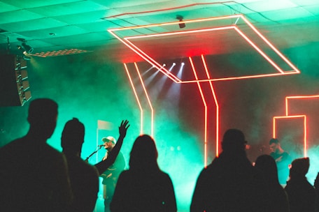 Close-up of a music artist performing under colorful neon lights on stage.